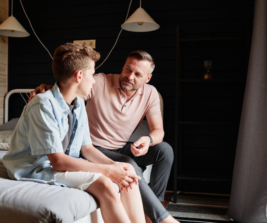 A father listening and talking with his older teenage son at home
